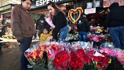 在美国加州洛杉矶的南加州花卉市场，一名妇女当地时间周二向商贩购买鲜花。（图取自法新社）
