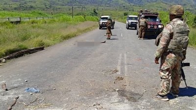 巴布亚新几内亚警察局于周一发布的照片，显示警察在瓦巴格镇附近巡逻时，发现路上有一具尸体。警方表示目前一共发现64具尸体。（图取自法新社）