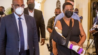 海地前总统莫伊兹2021年7月22日的天主教悼念仪式后，手臂受伤的莫伊兹遗孀玛蒂娜，在总理亨利的陪同下离开。（法新社档案照）