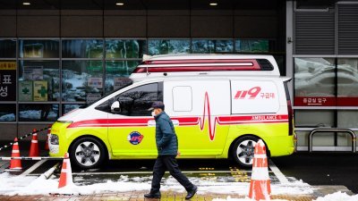 韩国首都首尔市的市民，周四经过一辆停在医院外的救护车。（图取自法新社）