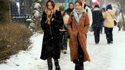 1月31日在哈萨克最大城市阿拉木图，妇女们于降雪期间沿著街道行走。（图取自法新社）