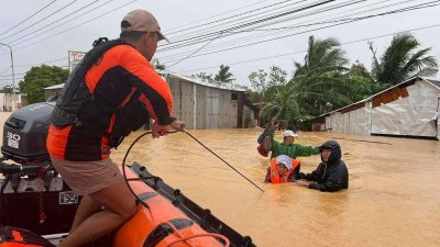 人为的气候变化使天气模式变得更加强烈。图为菲律宾中部萨马岛北部卡塔曼镇的一个村庄，在去年11月发生水灾，海岸警卫队人员协助一名老年居民，离开几乎被水淹没的家。（图取自法新社）
