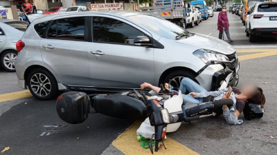 华妇骑摩哆与轿车相撞后倒地，小腿卡在摩哆停车架中。