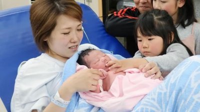 日本大阪府和泉市一家医院里，一名母亲抱著刚出生的婴儿。（图取自法新社）