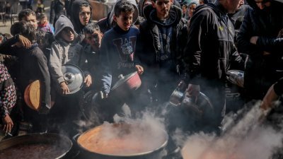 巴勒斯坦人周一聚集在加沙地带北部的拜特拉希亚（Beit Lahia），排队等候领取援助食品。（图取自法新社）