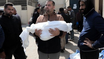 在加萨中部代尔巴拉赫的阿克萨医院外，一名男子周三抱著一名在以色列轰炸中丧生的儿童尸体。（图取自法新社）