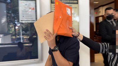 被告莫哈末法兹里于周四早上到亚罗士打第2地庭面控，离开法庭时用文件遮挡面部。