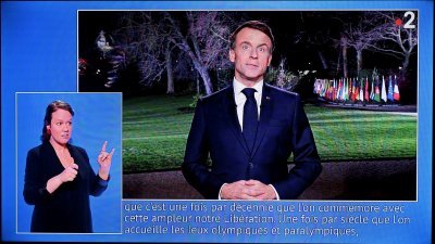 截取自法国电视二台的视频截图显示，法国总统马克龙在总统府爱丽舍宫花园发表新年致辞，而他的身后是2024年夏季奥运会将展示的各国会旗。（图取自法新社）