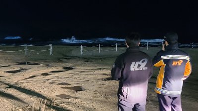 韩国紧急救援人员周一晚在江陵的海滩巡逻。（图取自韩联社/法新社）