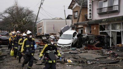 消防队员周三在日本石川县珠洲市遭受海啸破坏的住宅区展开搜救行动。（图取自共同社社/路透社）