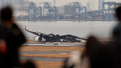 撞机事故中的日航客机，机身完全烧毁剩下机翼，周三仍在羽田机场的跑道上，等待调查和善后。（图取自路透社）