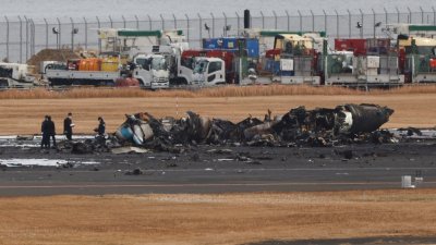 调查人员周三早上在羽田机场调查撞机事故，在海上保安厅飞机残骸周围搜证。（图取自路透社）