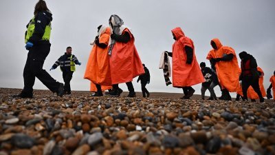 一名英国移民执法官员（左）和一名Interforce安全官员（左）护送试图穿越英吉利海峡的非法移民，他们在海上被皇家全国救生艇协会 (RNLI) 的救生艇救起。（图取自法新社档案照）