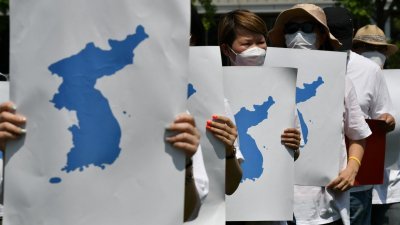 2020年6月13日，支持韩朝统一的韩国人士在活动中举著完整朝鲜半岛地图的标语牌，庆祝2000年6月历史性的韩朝峰会，还有时任韩国总统金大中和朝鲜最高领导人金正日发表联合和平宣言20周年。（图取自法新社档案照）