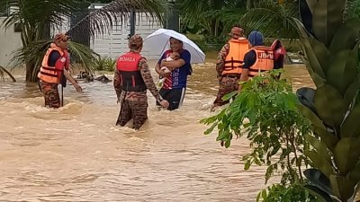 救援人员协助灾黎迁至临时疏散中心。