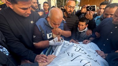 在周日举行的葬礼上，半岛电视台驻加沙办事处主任瓦埃尔站在儿子的遗体旁，悲痛地握著儿子的手哭泣。（图取自路透社）