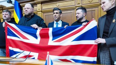 英国首相苏纳克（中）当地时间周五在乌克兰国会发表演说，赠予一面有英国政府所有内阁官员签名的英国国旗，象征英乌“坚不可摧的同盟”。（图取自中央社/英国首相府）