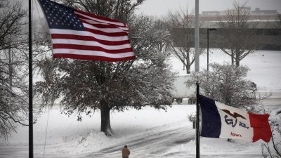 暴风雪当地时间周五吹袭美国中西部北方多数地区，在艾奥瓦州，一名居民走在一片白皑皑的道路上。（图取自路透社）