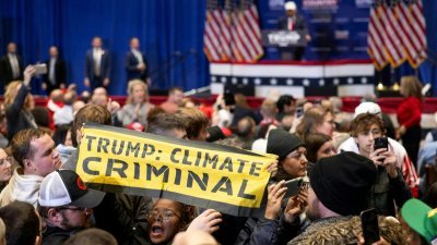 美国前总统特朗普为自己选举造势时，一名抗议人士在现场拉开写有“特朗普，气候罪犯”的布条示威，但很快就被警卫拦下。（图取自法新社）