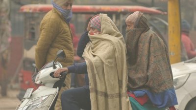 印度旁遮普邦阿姆利则市的街道上，乘摩哆出行的民众在寒冷的冬天披著厚围巾御寒。（图取自法新社）