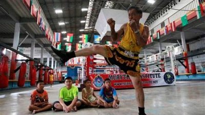 2012年8月26日，在曼谷泰拳学院的一名教练在训练期间向孩子们展示一些入门姿势。（图取自路透社档案照）