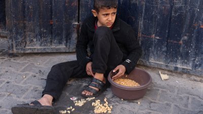 加沙地带南部拉法市一名男孩，不小心打翻食物，一脸难过地坐在地上。（图取自路透社）