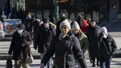美国纽约市民周三穿著厚实的御寒衣物，在严寒气温中出行，口中不断呼出白气。（图取自法新社）