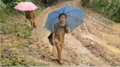 2名国小生冒雨脚踩烂泥巴路上学。