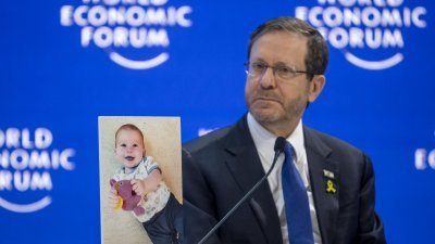 以色列总统赫尔佐格周四在瑞士达沃斯举行的世界经济论坛上，展示一张遭到哈马斯绑架的10个月大婴儿的照片。（图取自法新社）