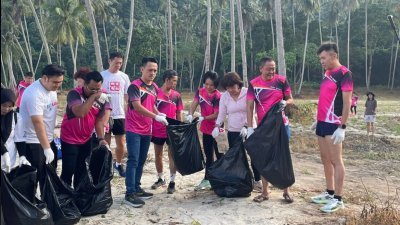 吴俊益（右6）与公正党峇都加湾区部成员在海边拾垃圾。