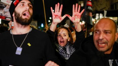 在以色列总理内塔尼亚胡位于耶路撒冷的住宅外，人质家属和支持者周一举行的抗议活动上，一名示威者举起涂著红色的双手，上面写著“时间不多了”。（图取自路透社）