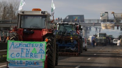 在图卢兹以南的卡博讷附近，一辆拖拉机上挂著“愤怒的农民”的横幅，农民们在周一继续封锁A64高速公路，抗议税收和收入下降。（图取自法新社）