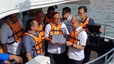 法米（右）乘游船河测试马六甲旅游区的移动网络服务（语音通话）是否有出现中断问题。