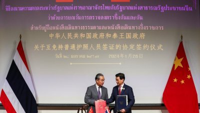 中国外交部长王毅与泰国外交部长帕恩普里于周日，在曼谷的泰国外交部举行的互免签证协议签字仪式上握手。（图取自路透社）
