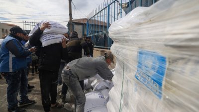 在位于加沙地带南部拉法的近东救济工程处中心，流离失所的巴勒斯坦人于周日领取粮食援助。（图取自法新社）