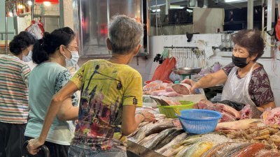 林秋月（右）在新加坡红山景第115座巴刹与熟食中心卖鱼，许多街坊在清晨时分上门光顾，挑选新鲜鱼。