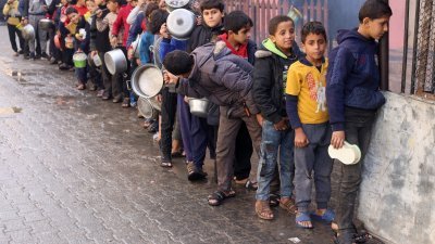 加沙的孩子们在排队领取国际食物救济。（图取自路透社）