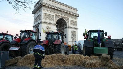 法国农民工会周五在首都巴黎举行抗议活动，用拖拉机和成捆的乾草堵住凯旋门前的香榭丽舍大道，两名警员到现场查看。（图取自法新社）
