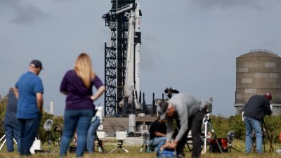 在美国佛罗里达州卡纳维拉尔角，搭载载人龙飞船的猎鹰9号火箭周六停在肯尼迪航天中心发射台，摄影师架设远端摄影机准备拍摄升空画面。（图取自法新社）