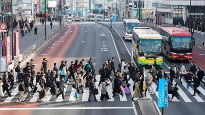 早上上班的人们走在斑马线上，穿越日本东京的大马路。（图取自法新社）