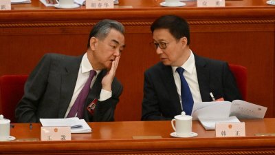 中国十四届全国人大二次会议周二早在北京人民大会堂开幕，中国外长王毅（左）与中国国家副主席韩正交谈。（图取自法新社）