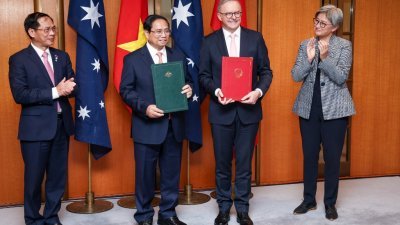 越南总理范明政（左2）与澳洲总理阿尔巴尼斯（右2）周四在堪培拉议会大厦交换文件后合影，澳洲外交部长黄英贤（右）和越南外交部长裴青山（左）在旁陪同。（图取自法新社）