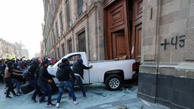 周三在墨西哥城为2014年失踪的43名学生伸张正义的示威者，推动一辆皮卡车，撞破国家宫的木门。（图取自法新社）