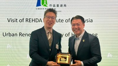 倪可敏(右) 赠送纪念品予香港市区重建局商务执行董事区俊豪。