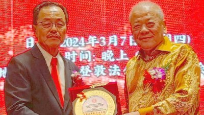 华总总会长吴添泉（右）从沙巴古田公会会长郑仁保手中接过纪念盾。