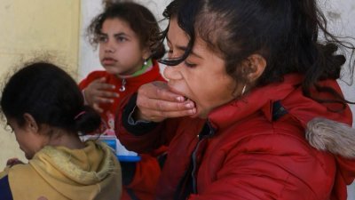 巴勒斯坦的难民儿童，周五在加沙南部拉法的一个食品分发点附近，大口吃下所领取的食物。目前加沙1/4的人口正处于饥荒边缘。（图取自法新社）