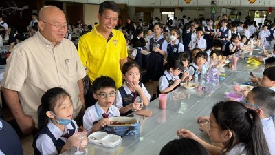 黄吉和（左）与家协理事张文忠巡视学校，与正在食堂用餐的学生互动交流。
