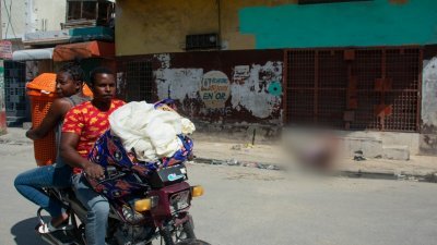 上周六在海地首都太子港，帮派暴力愈演愈烈，居民带著家当撤离家园，路上可见受害者的尸体。（图取自法新社）