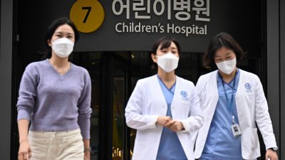 数名医护人员周一步出首尔一家儿童医院。（图取自法新社）