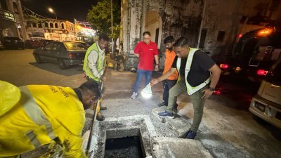 黄家杰（中）与怡保市政厅承包商一同到谦街巡视沟渠清理工作。